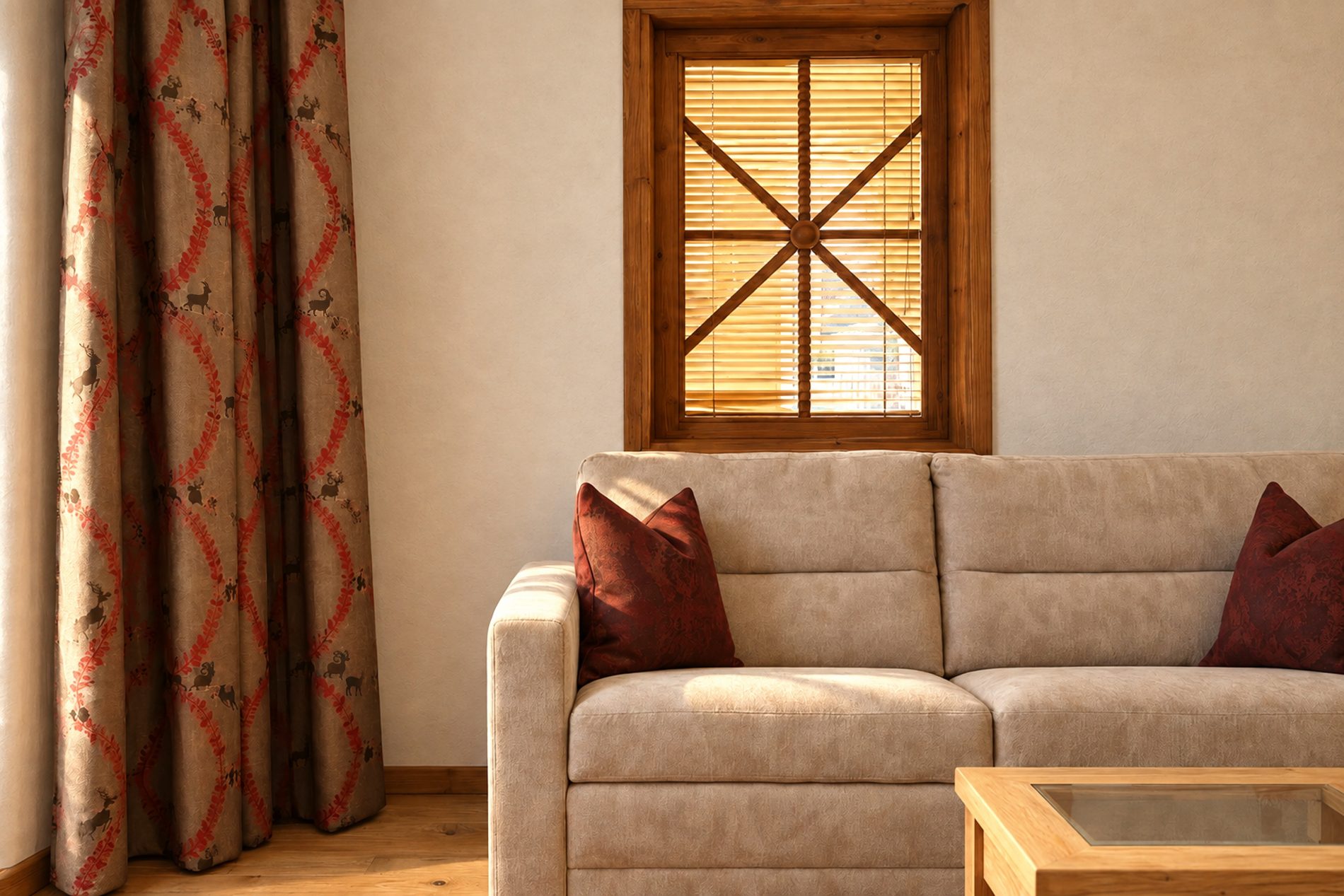 Sofa mit roten Zierkissen und Couchtisch unter dem Sprossenfenster in der Suite Magdalena des Hotels DreiSonnen in Serfaus