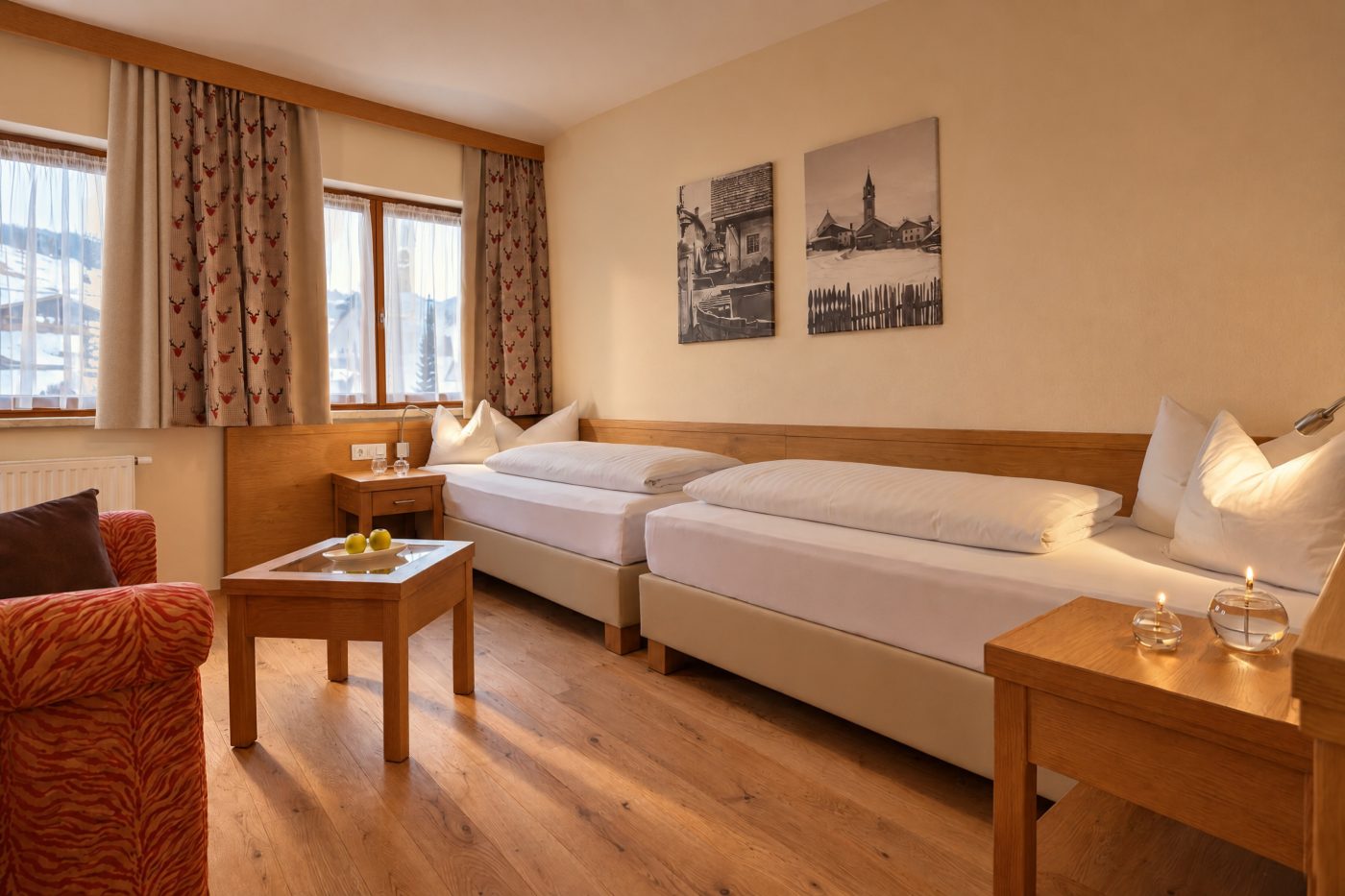 Kinderzimmer mit zwei Betten, Couchtisch, Sessel und Schwarz-Weiß-Bildern in der Suite Magdalena des Hotels DreiSonnen in Serfaus