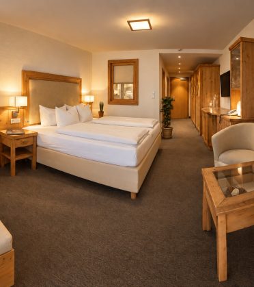 Suite Maria Theresia im Hotel DreiSonnen in Serfaus mit Doppelbett, zwei Sesseln und Holzmöbeln aus Zirbe