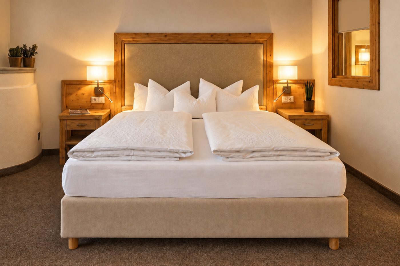 Doppelbett mit gepolstertem Kopfteil im Holzrahmen, Nachttischen und Tischlampen in der Suite Maria Theresia des Hotels DreiSonnen in Serfaus