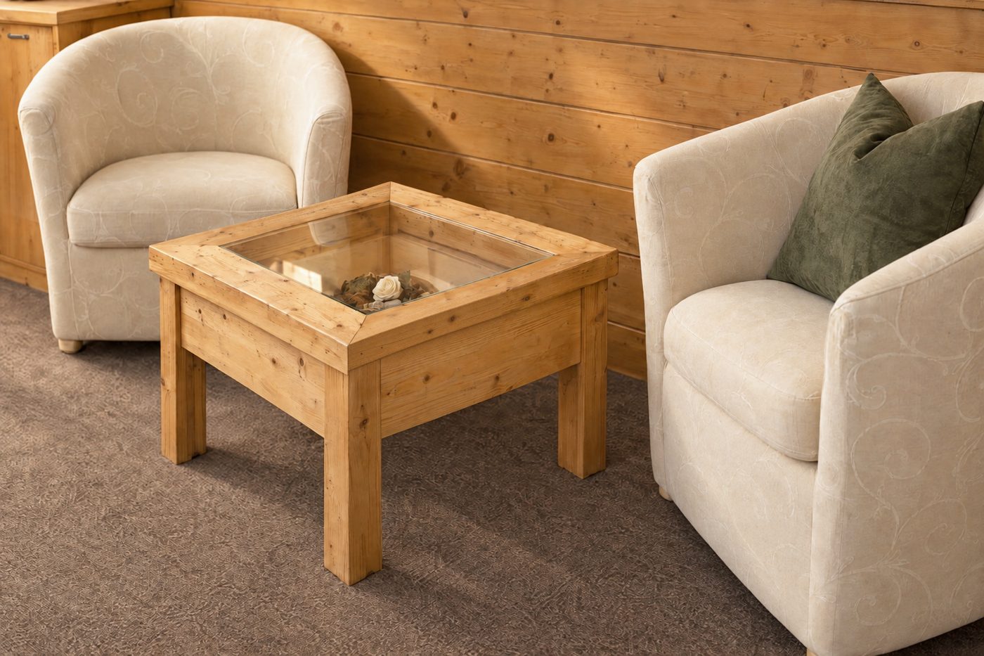 Zwei helle Sessel mit Couchtisch aus Holz vor der Holzvertäfelung in der Suite Maria Theresia des Hotels DreiSonnen in Serfaus