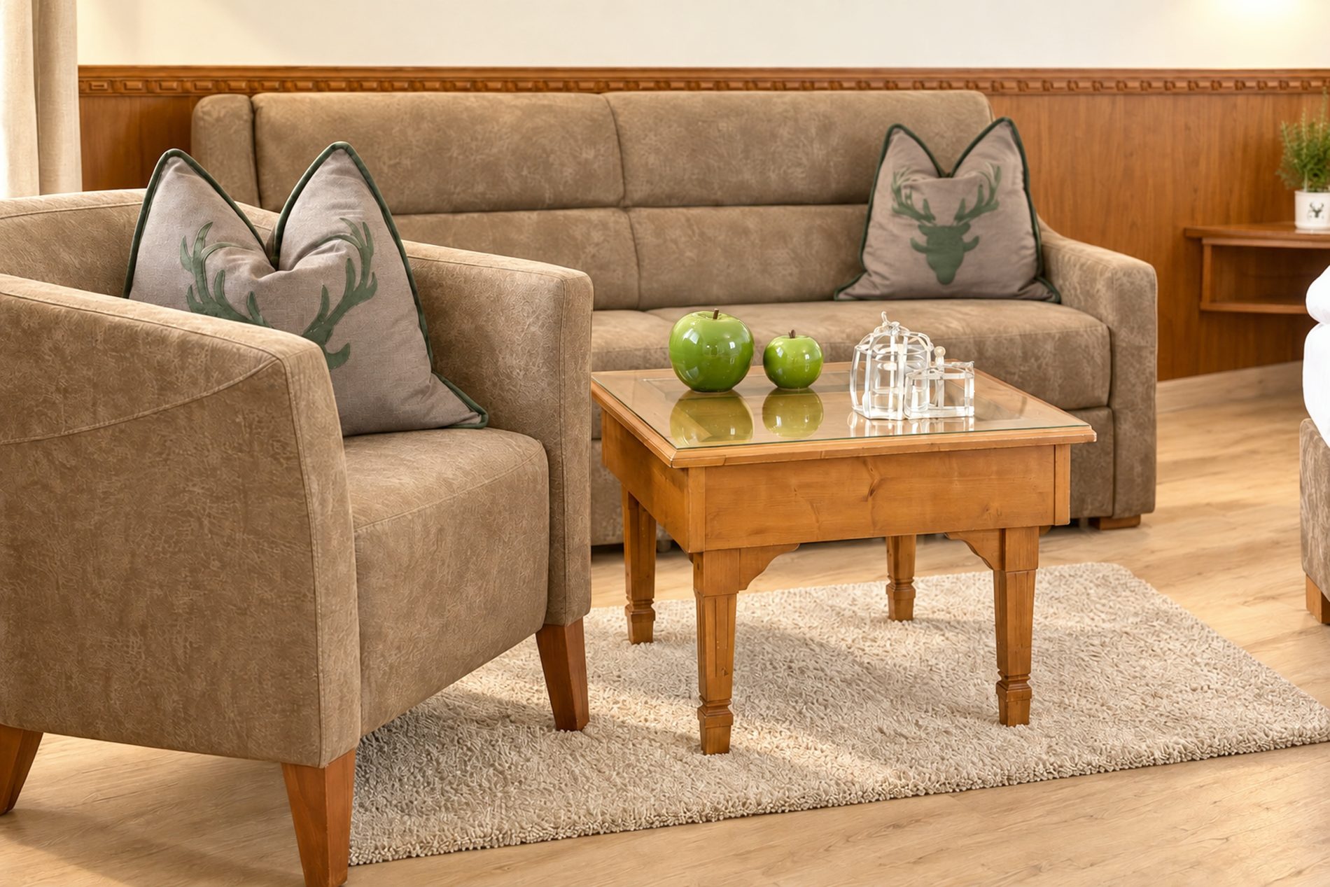 Sofa und Sessel mit Hirschmotiv-Kissen und Couchtisch mit Äpfeln im Zimmer Mona Lisa des Hotels DreiSonnen in Serfaus