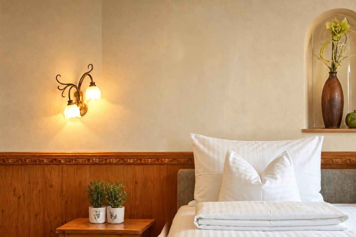Wandleuchte und Nische mit Vase über dem Bett im Zimmer Mona Lisa des Hotels DreiSonnen in Serfaus