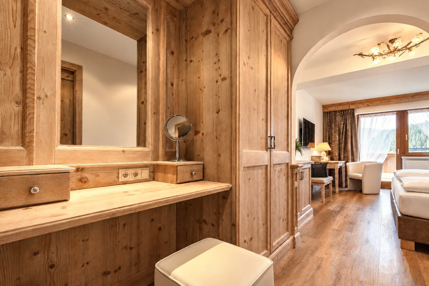 Schminktisch mit Spiegel, Hocker und Kleiderschrank aus Altholz in der Suite Schönbrunn des Hotels DreiSonnen in Serfaus