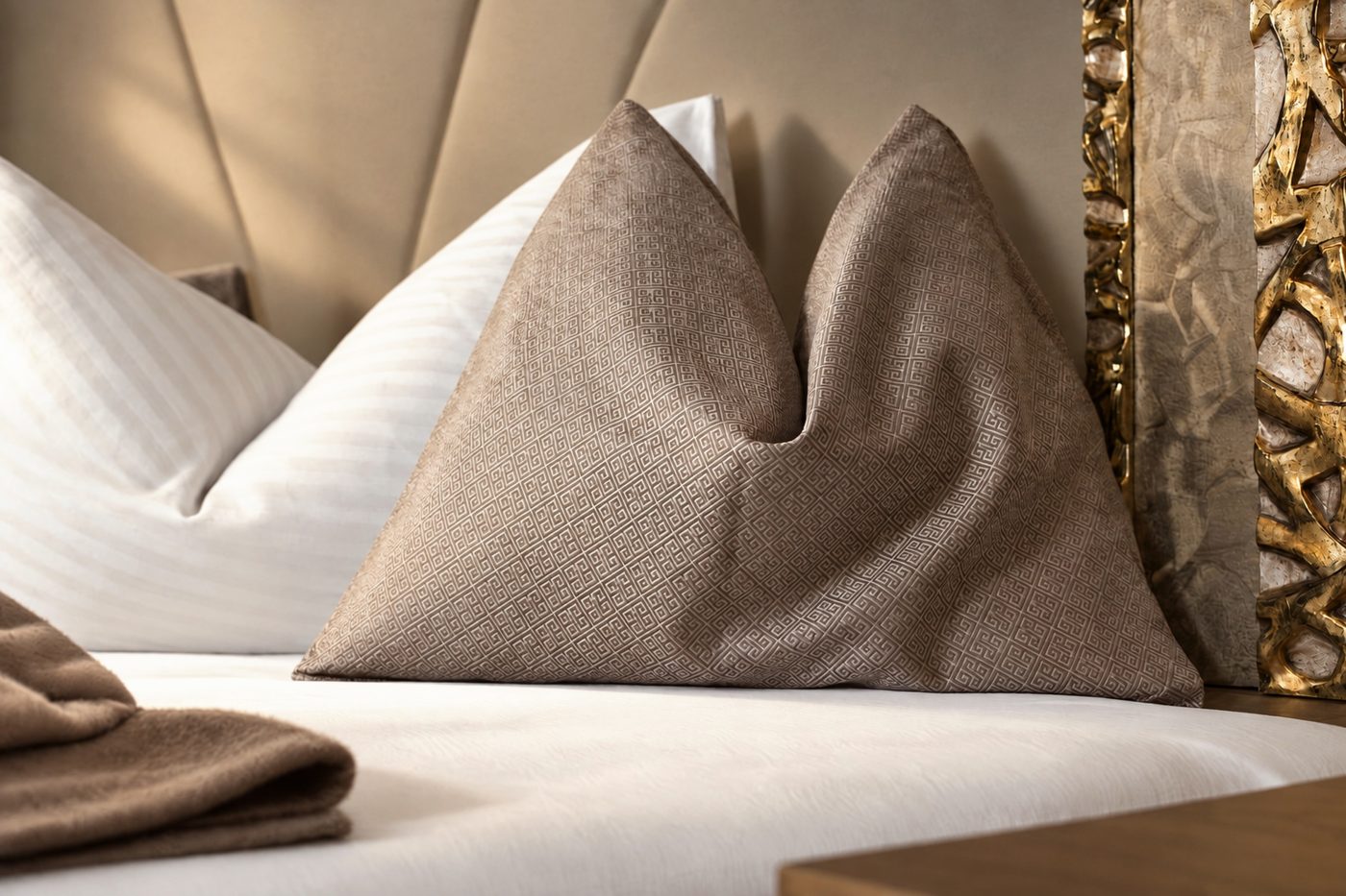 Kissen vor dem gepolsterten Kopfteil in der Suite Schönbrunn des Hotels DreiSonnen in Serfaus