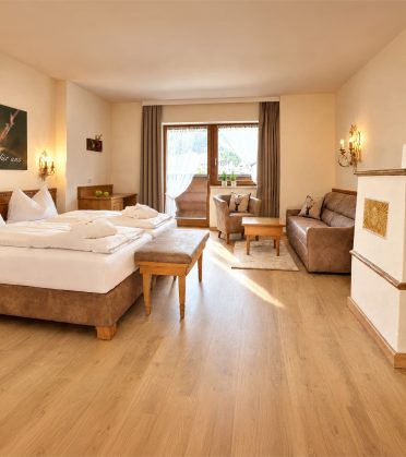 Komfort-Familienzimmer Valentina im Hotel DreiSonnen in Serfaus mit Sofa, Sessel, Couchtisch mit Sektkühler und Doppelbett