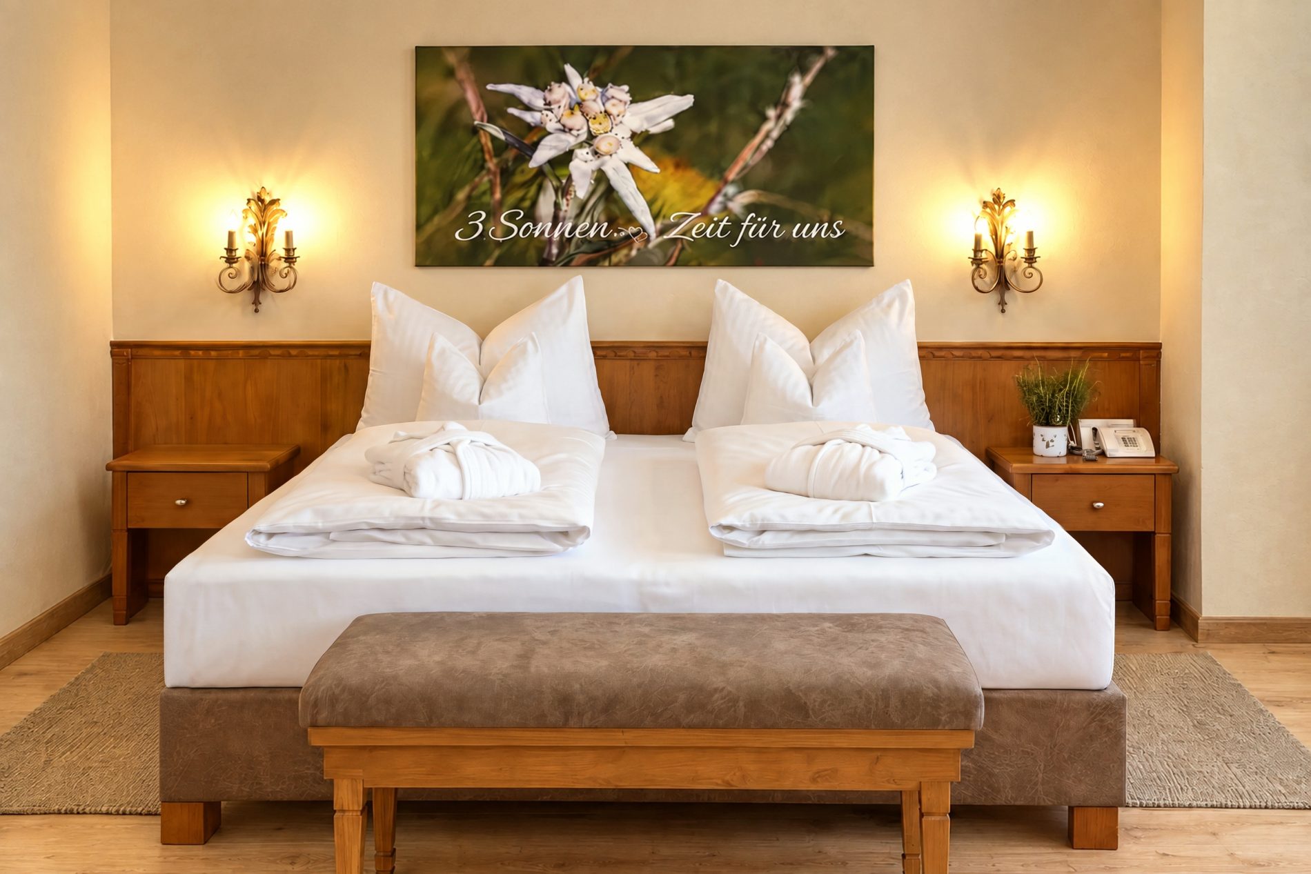 Double bed with edelweiss picture, wall lights and bench in the room Valentina at Hotel DreiSonnen in Serfaus