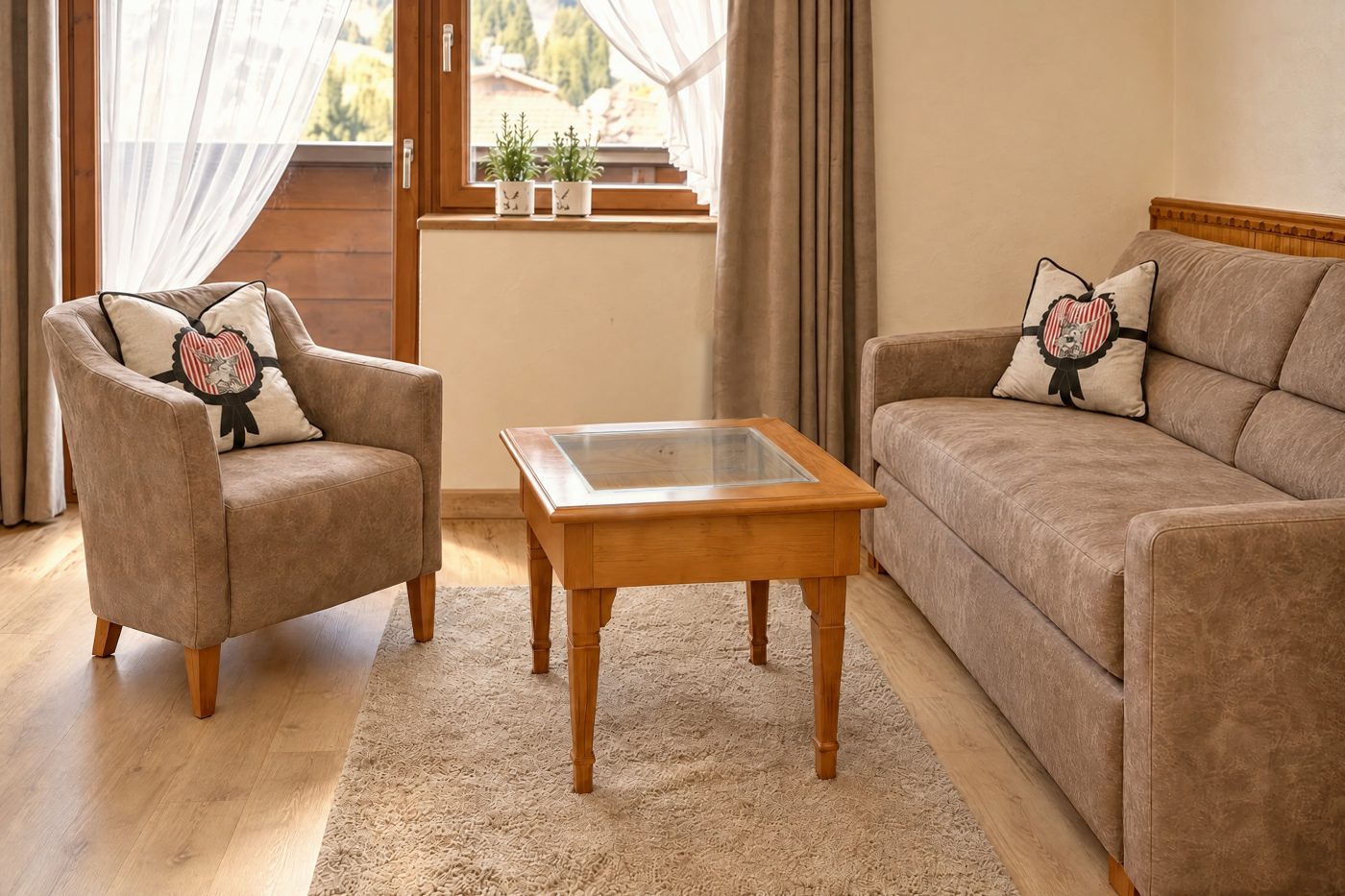 Sofa and armchair with coffee table and champagne cooler in front of the balcony door in the Valentina room at Hotel DreiSonnen in Serfaus