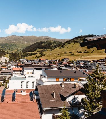View over the roofs of Serfaus to green slopes and mountains in summer.
