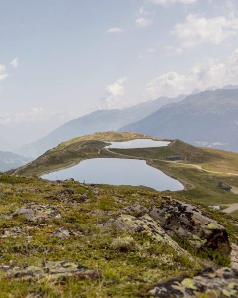 View across a mountain meadow to two mountain lakes below the peaks.