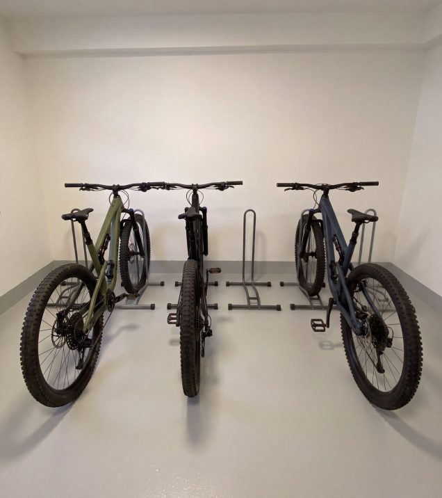 Three mountain bikes in the bike stands of the bike room at Hotel DreiSonnen