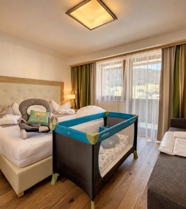 Familienzimmer im Hotel DreiSonnen mit Doppelbett und aufgebautem Babybett.