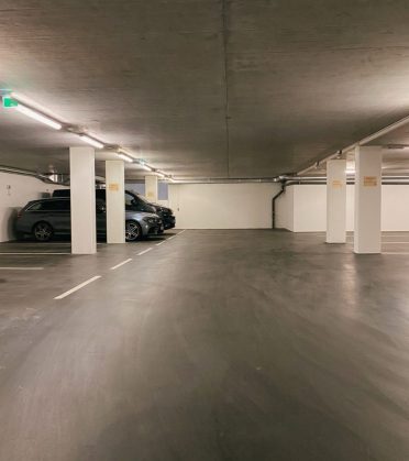 Garage of Hotel DreiSonnen with light-coloured pillars and parked cars