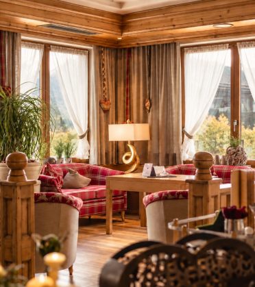The lobby of Hotel DreiSonnen with red check armchairs, a wooden banister and bright windows.