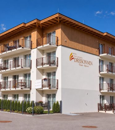 The staff house of Hotel DreiSonnen with wooden cladding and balconies under a blue sky, the lettering DreiSonnen Team-Resort on the wall.