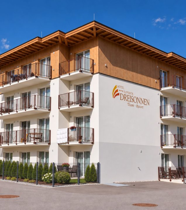 The staff house of Hotel DreiSonnen with wooden cladding and balconies under a blue sky, the lettering DreiSonnen Team-Resort on the wall.