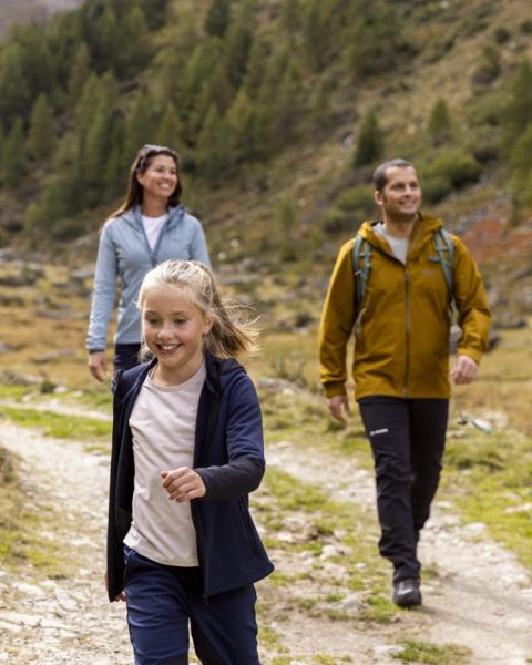 A family hiking on a path through the mountain landscape.