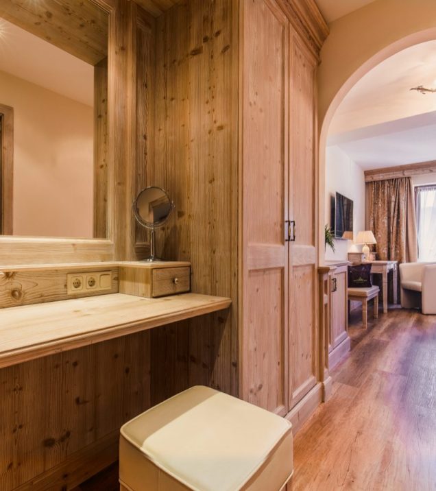 Dressing table and wardrobe in light wood in a room at Hotel DreiSonnen, in front of them an upholstered stool.